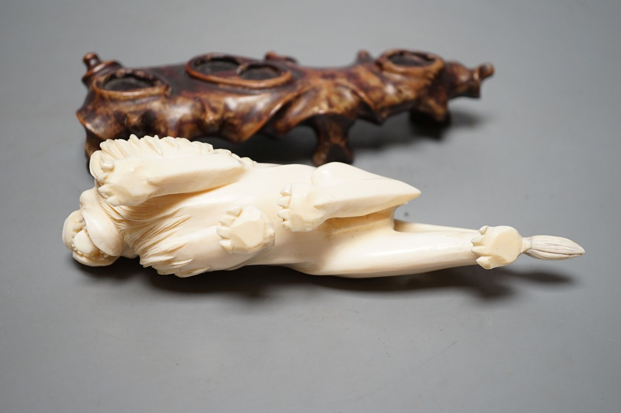 A Chinese ivory figure of a lion, on wooden stand, early 20th century, stand 20 cms wide.
